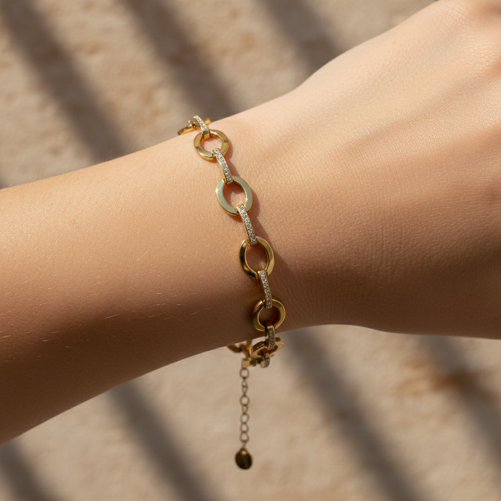 18K gold plated bracelet featuring alternating polished oval links and crystal-encrusted bar connectors on a white surface.