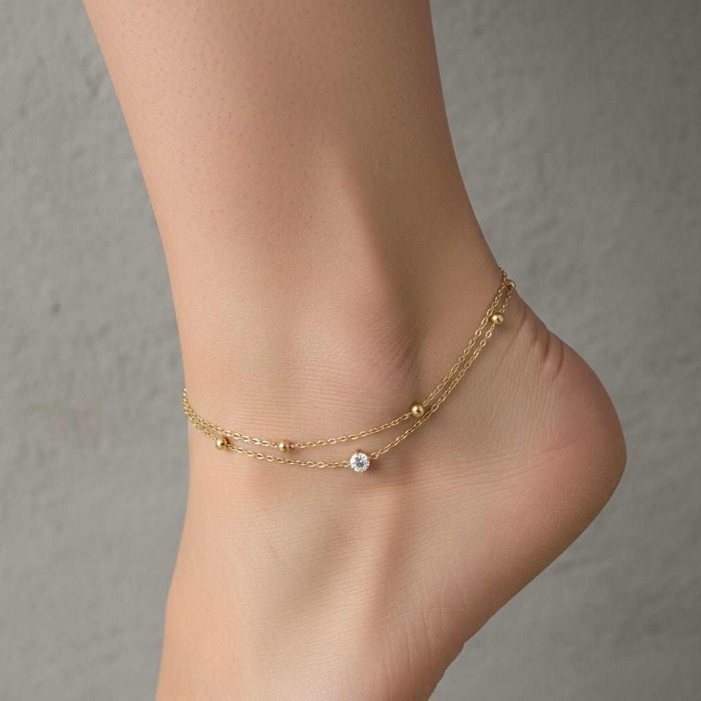 18K gold plated double-layer anklet with one plain chain and one chain featuring a crystal charm and gold beads.