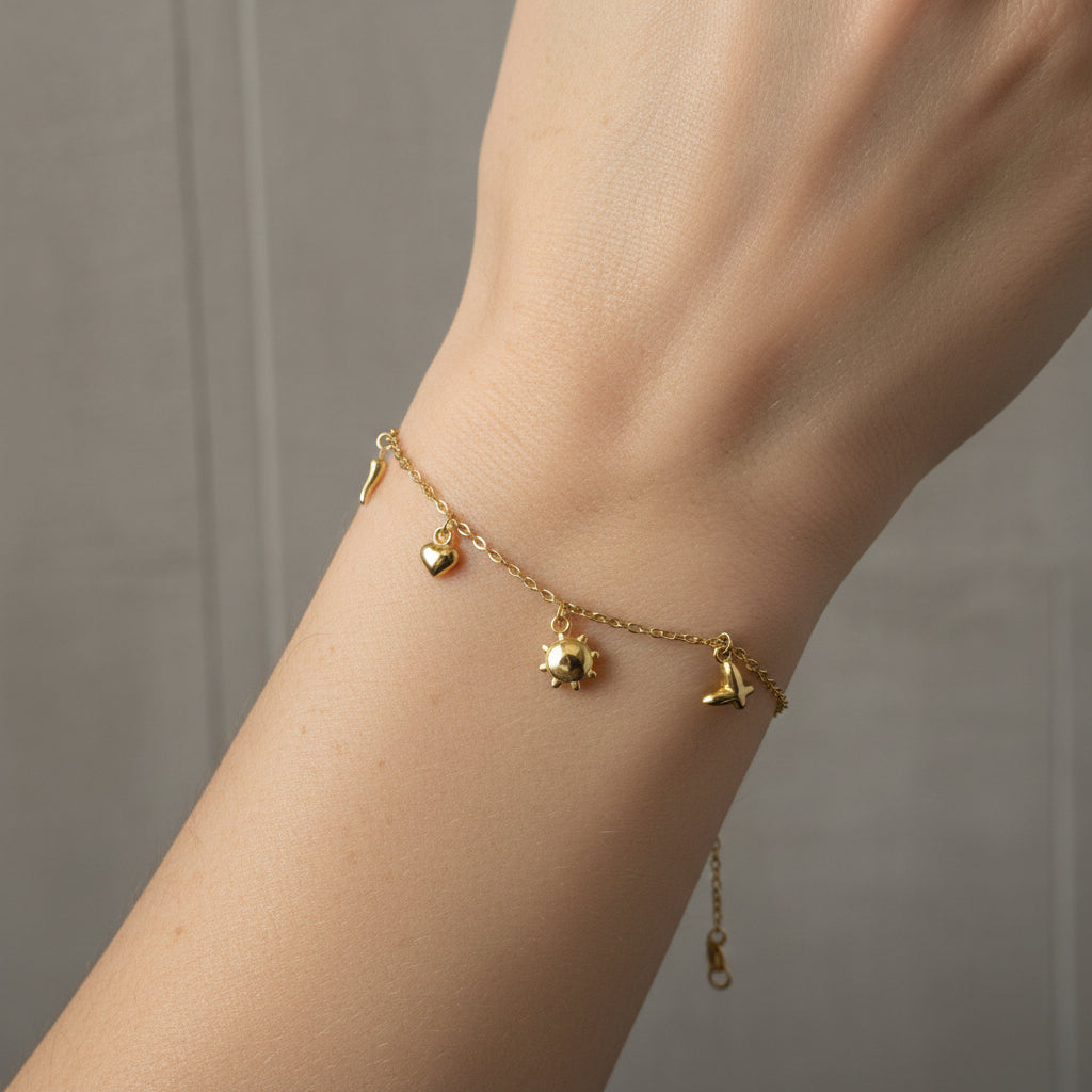 Treshire 18K gold plated Whimsical Charm Bracelet featuring sun, heart, and star-shaped charms on a gold chain, displayed on a white surface.