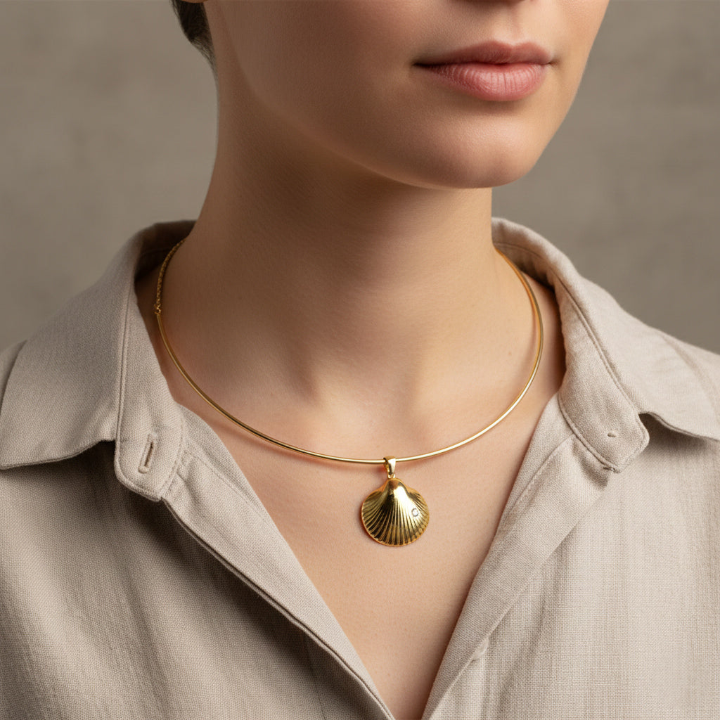 A woman wearing a structured 18K gold-plated torque choker featuring a central sculpted scallop shell pendant with a singular crystal accent.