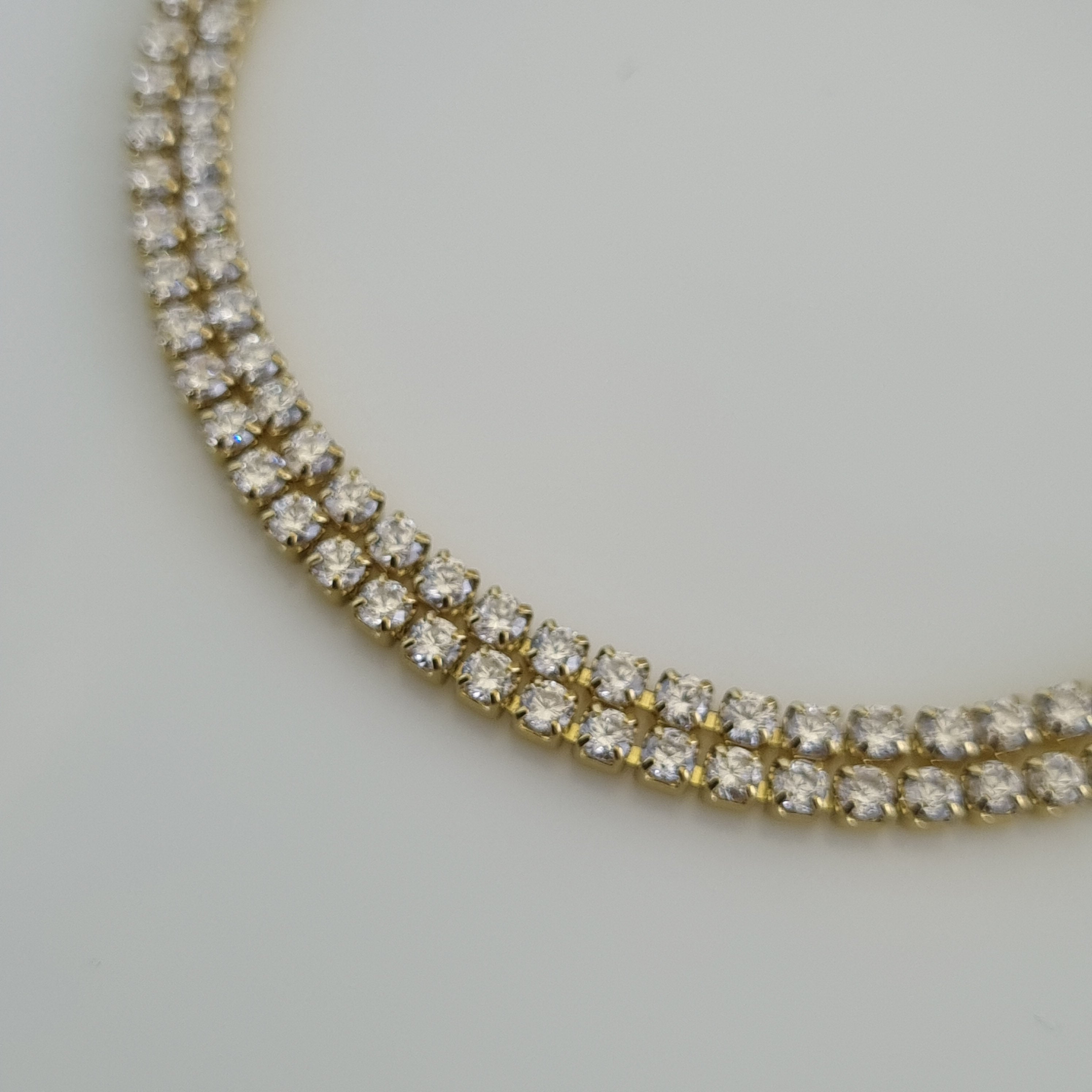 18K gold plated tennis bracelet featuring two parallel rows of brilliant-cut zirconia crystals and an adjustable lobster clasp.