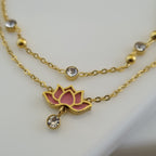 Gold necklace with pink lotus flower pendant on a white background