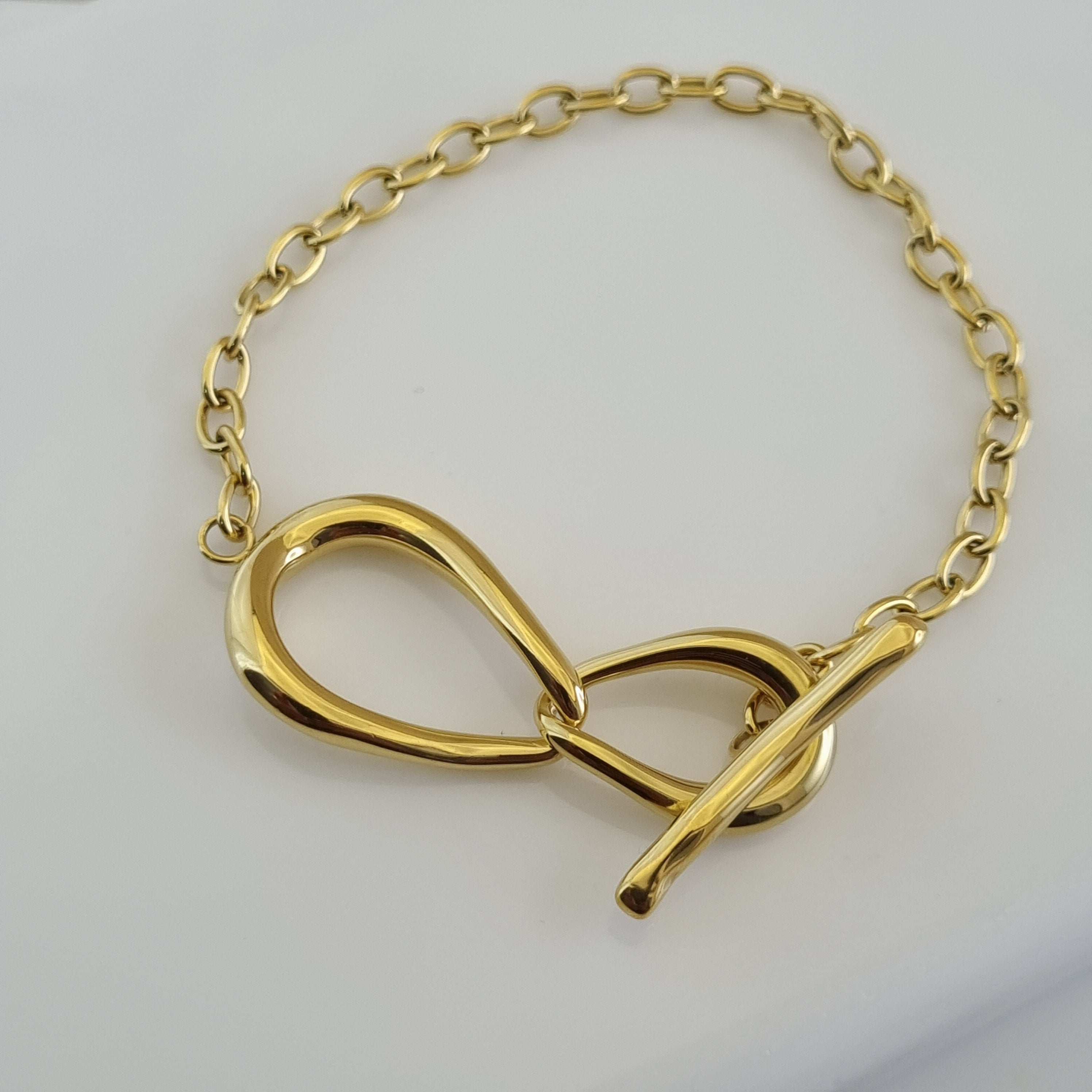 18K gold plated statement bracelet featuring a bold oval link chain and a large infinity loop toggle closure.