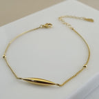 18K gold plated anklet with a central gold tube charm and two gold beads on a micro-box chain.