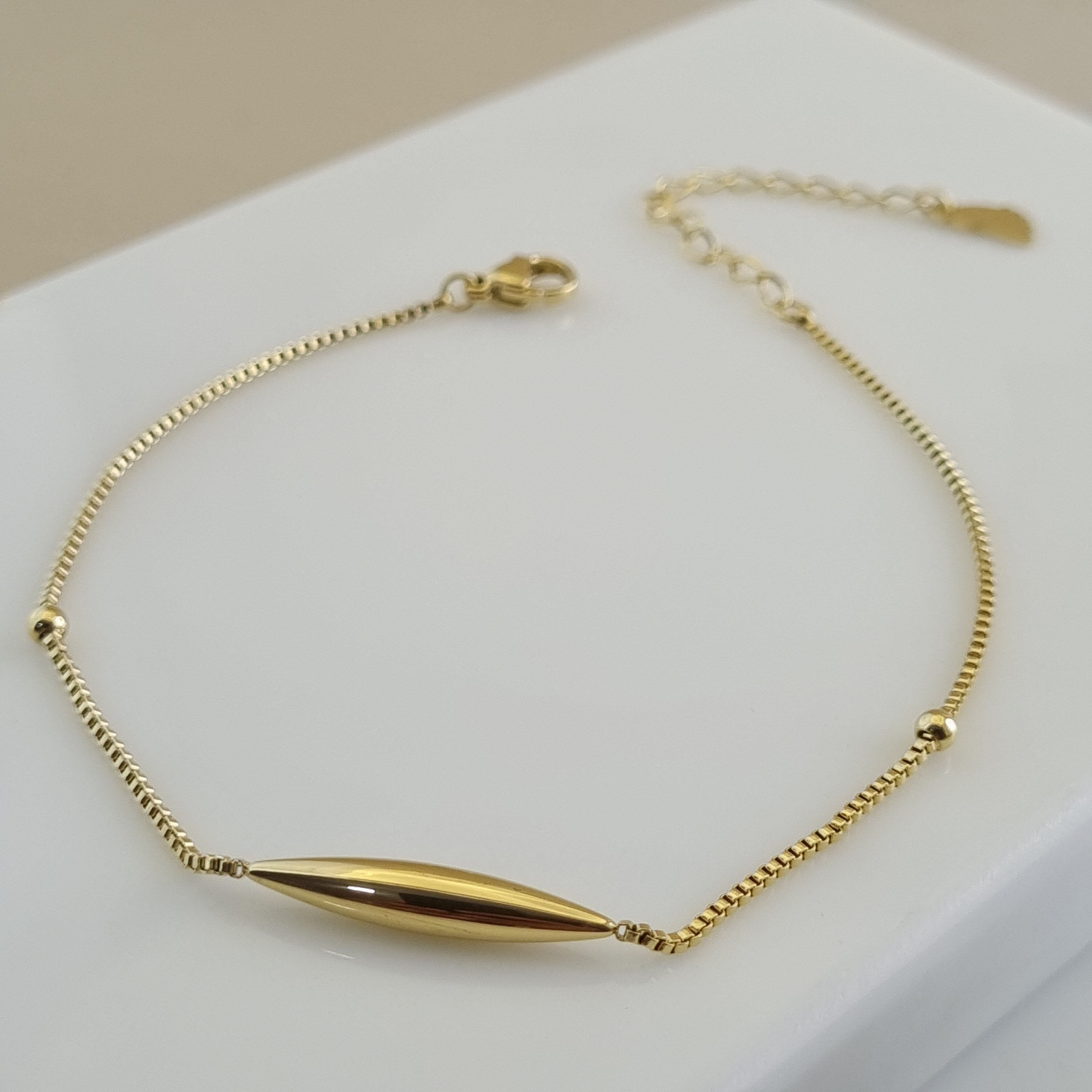 18K gold plated anklet with a central gold tube charm and two gold beads on a micro-box chain.
