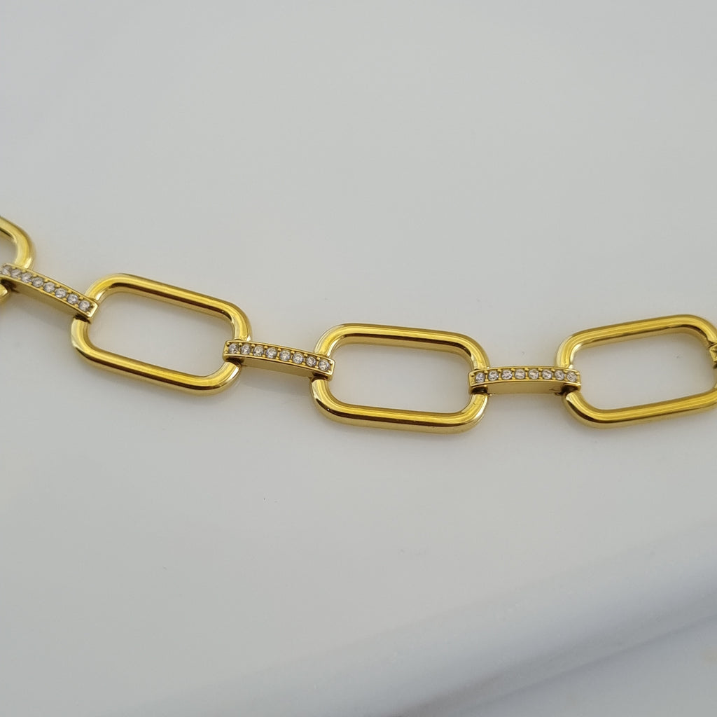 Treshire 18K gold plated elongated link bracelet with pave connector bars resting on a white marble surface.