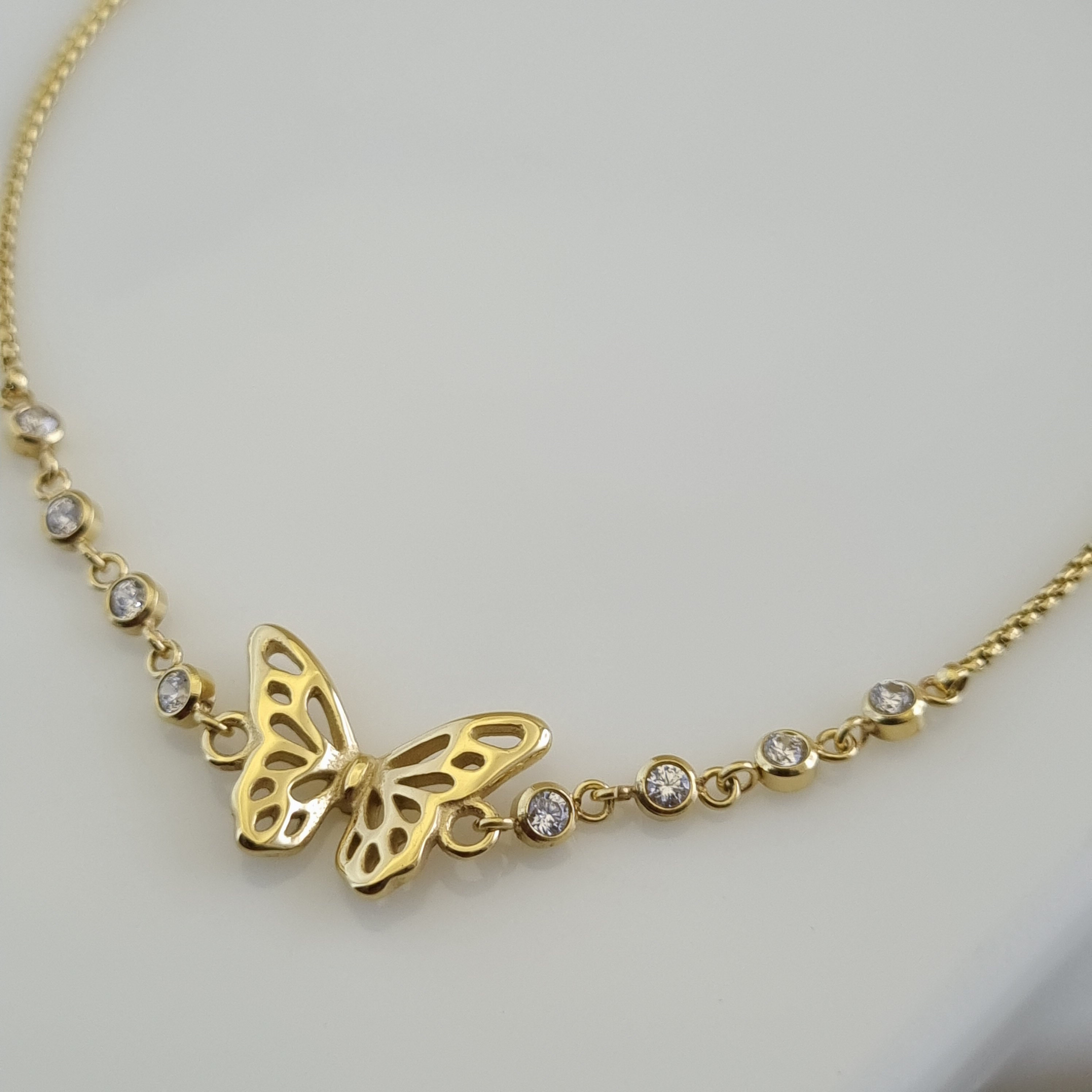 18K gold plated anklet featuring a butterfly charm and several bezel-set crystals on a delicate micro-box chain.