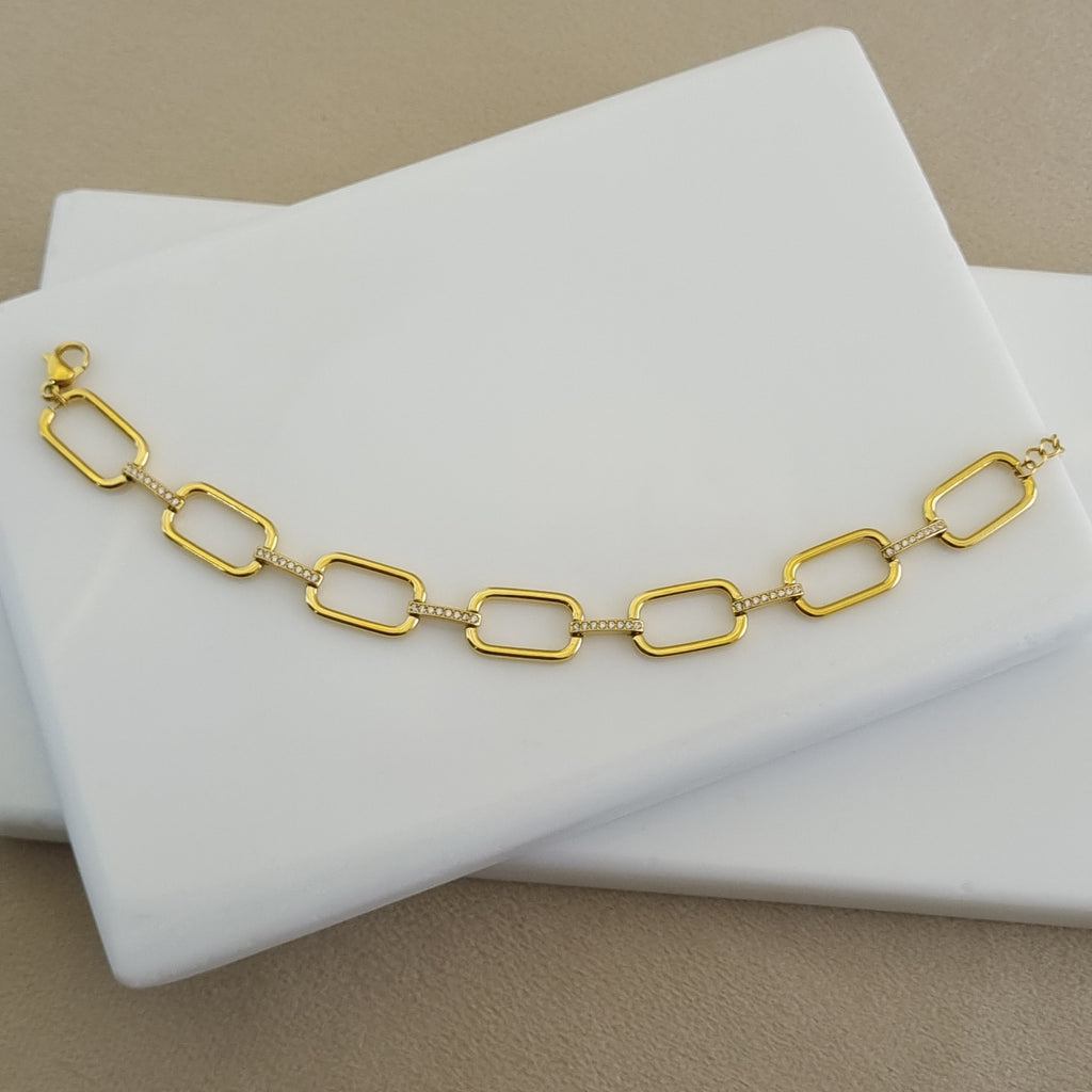 Treshire 18K gold plated elongated link bracelet with pave connector bars resting on a white marble surface.