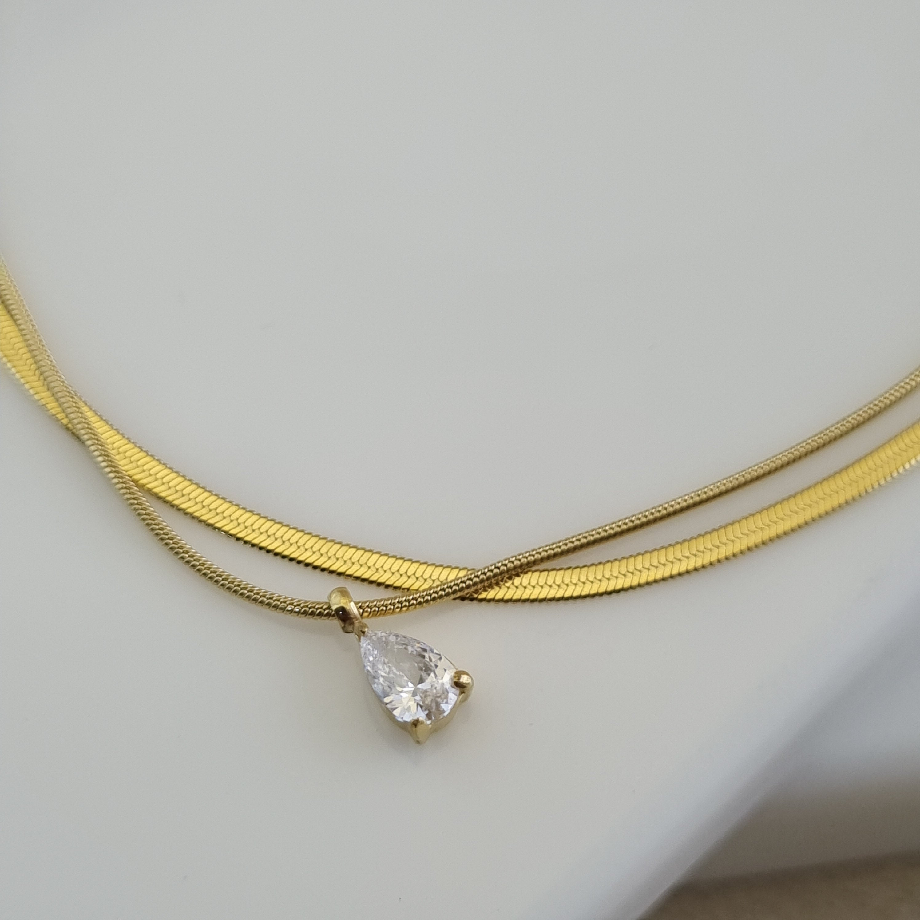 18K gold plated double-layer anklet with a flat herringbone chain and a pear-cut zirconia crystal charm.