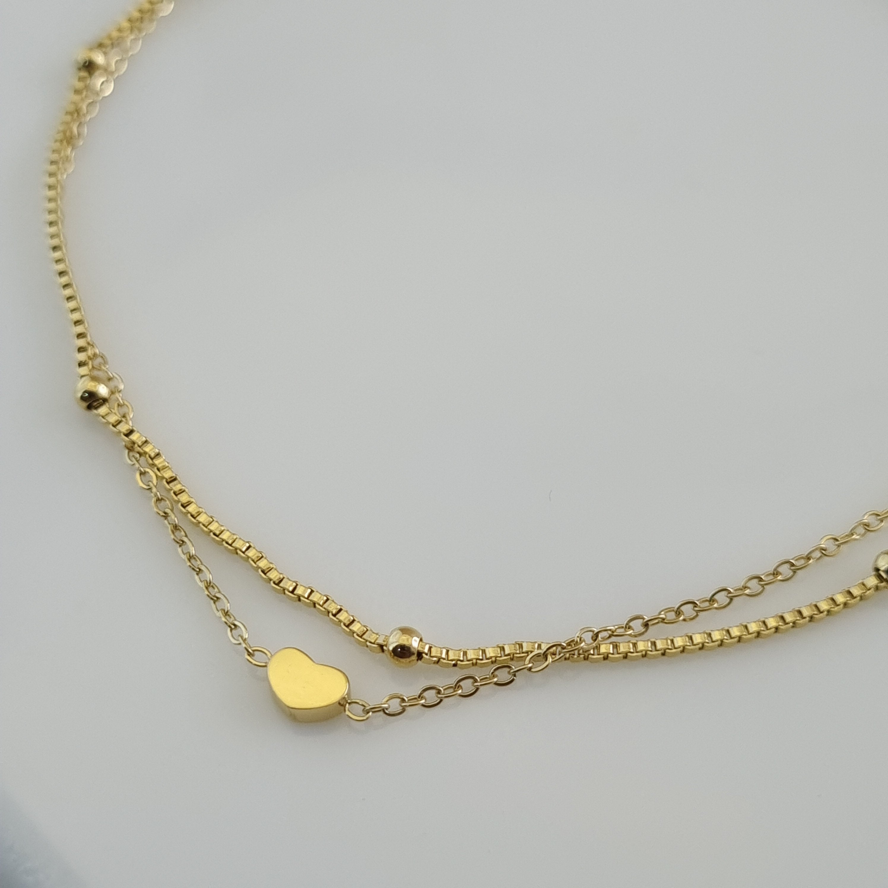 18K gold plated double-layer anklet with a box chain, cable chain, gold heart charm, and bead accents.