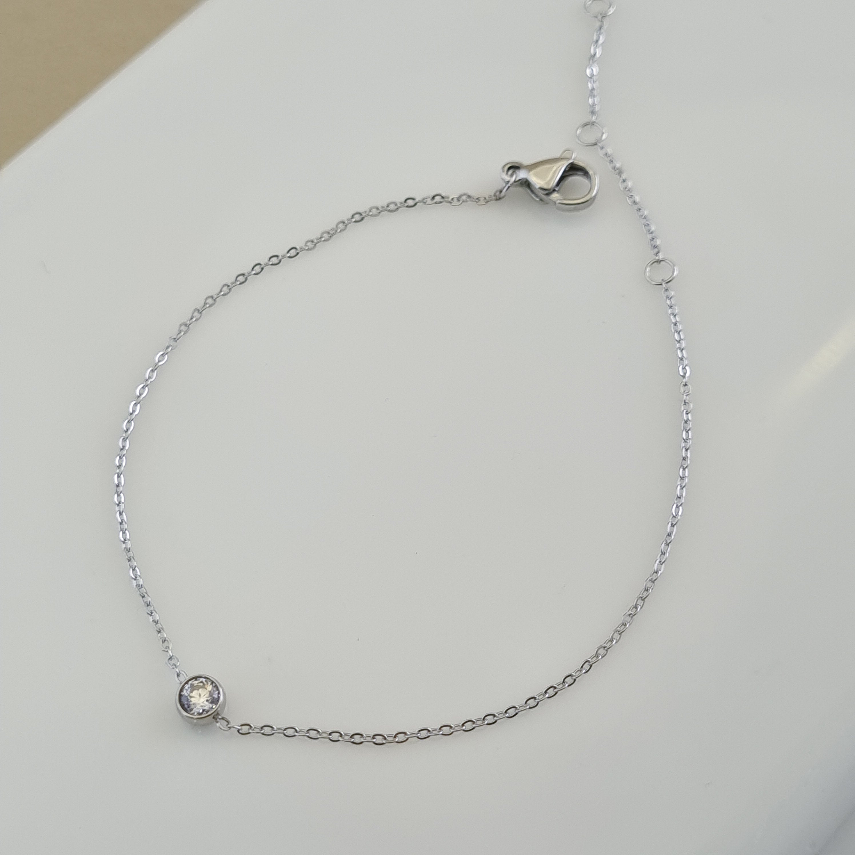 Treshire silver-tone solitaire bracelet with a single bezel-set crystal on a fine chain, displayed on a white surface.