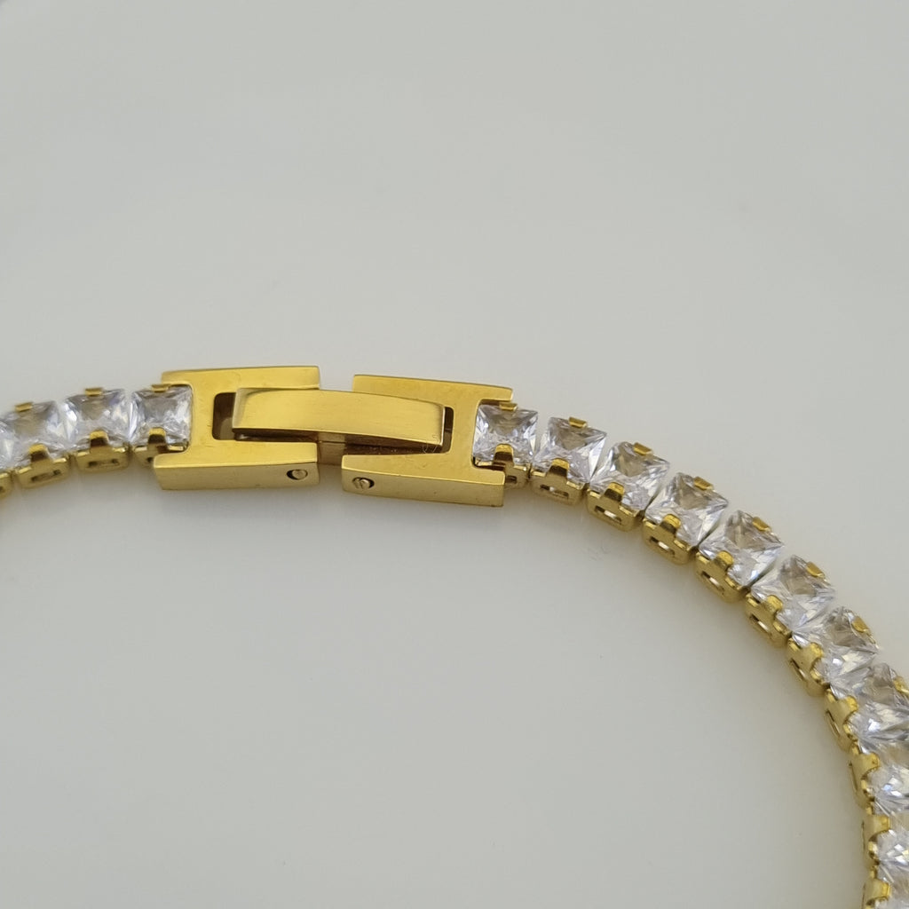 Gold bracelet with clear gemstones on a light gray background