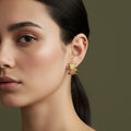 A woman with a sleek hairstyle wearing unique 18K gold-plated stud earrings featuring a horizontal stack of raw-edged golden bars.