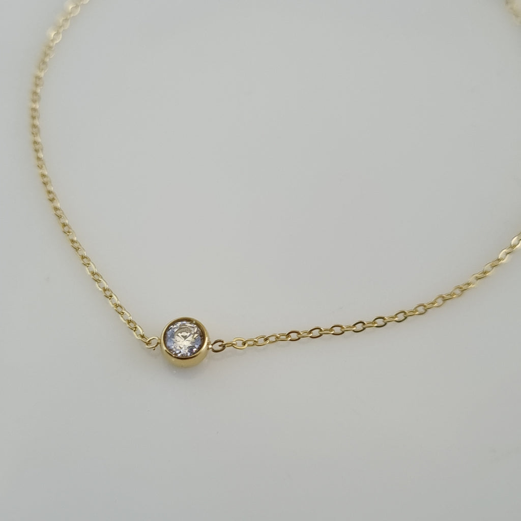 Treshire 18K gold plated Everyday Solitaire bracelet with a smaller bezel-set crystal on a fine gold chain, displayed on a white surface.