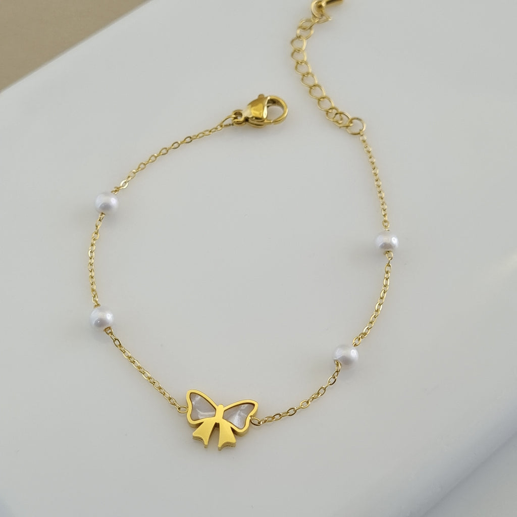 Treshire 18K gold plated bracelet with a Mother of Pearl bow charm and four stationed white pearls on a fine gold chain.