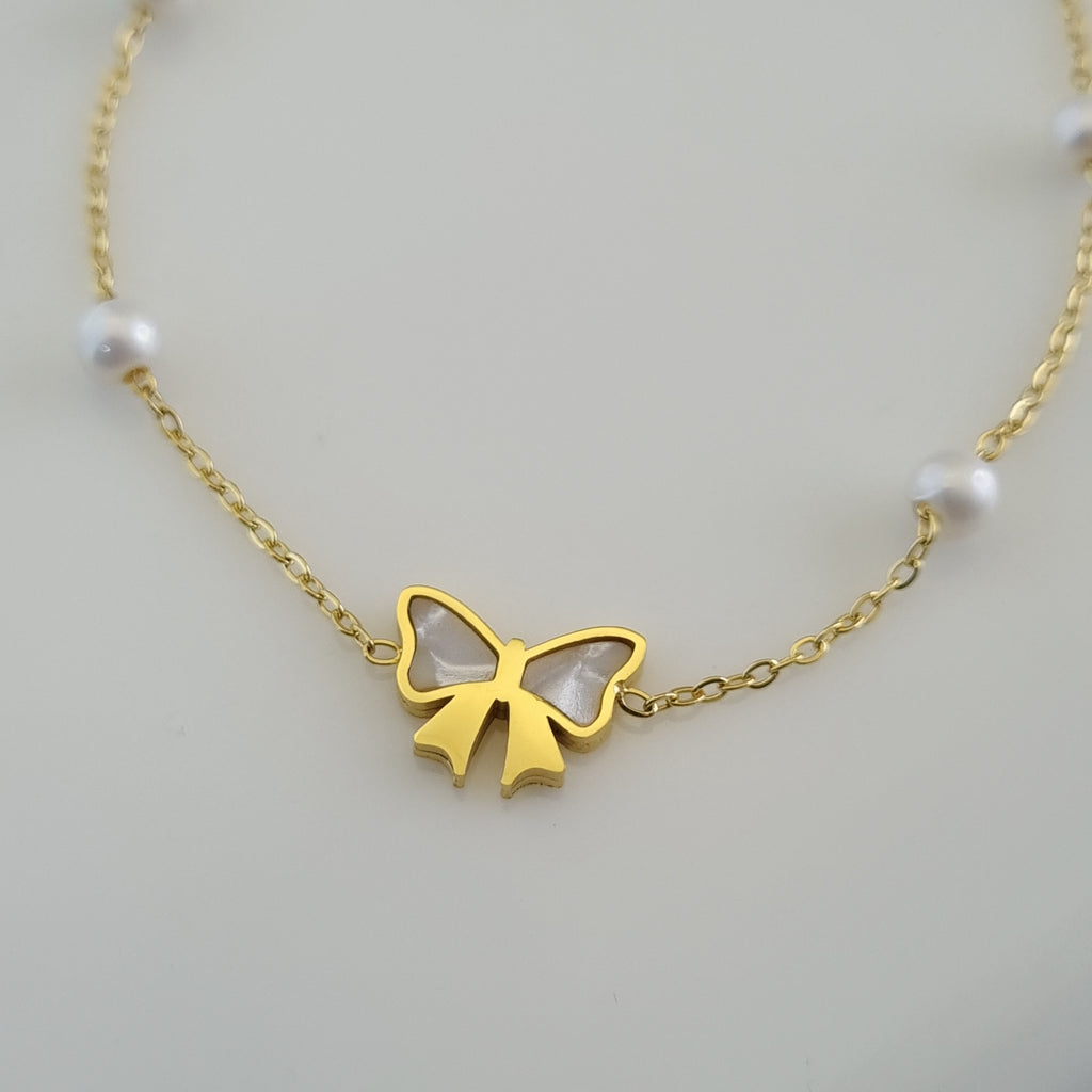 Treshire 18K gold plated bracelet with a Mother of Pearl bow charm and four stationed white pearls on a fine gold chain.