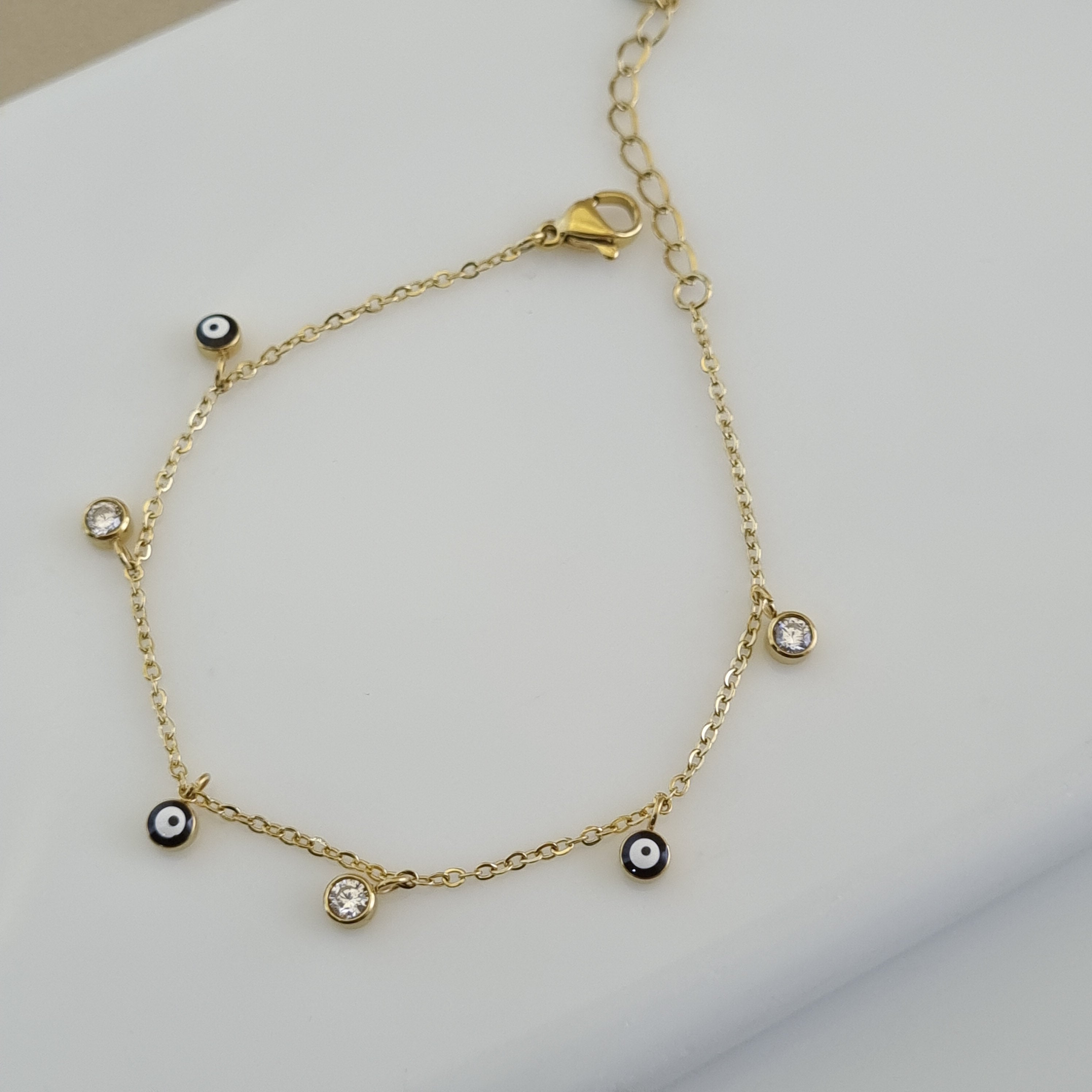 Treshire 18K gold plated Nazar bracelet with alternating blue evil eye charms and bezel-set crystals on a fine gold chain.
