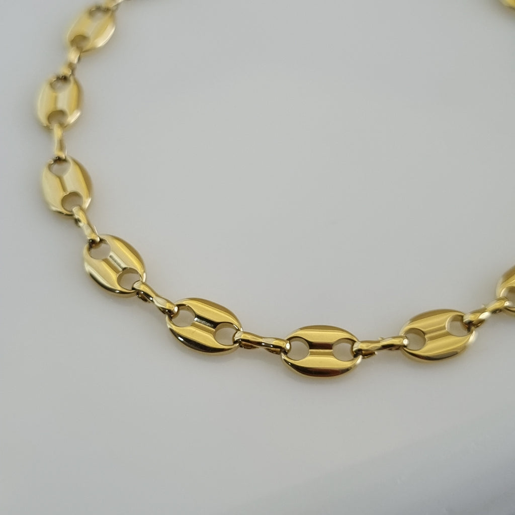 Treshire 18K gold plated Marina link bracelet with high-polish coffee bean style anchor links displayed on a white marble surface.