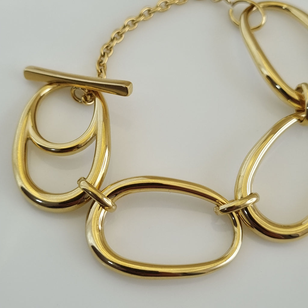 Treshire 18K gold plated bold bracelet featuring oversized sculptural ovoid links and a T-bar toggle clasp on a white surface.