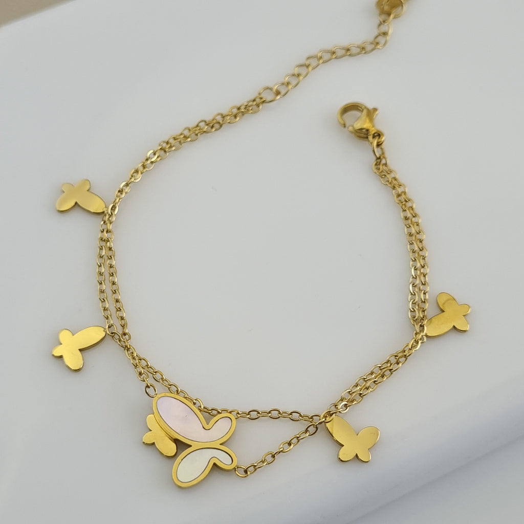 Treshire 18K gold plated double chain bracelet with a central Mother of Pearl butterfly and four gold butterfly charms displayed on a white surface.