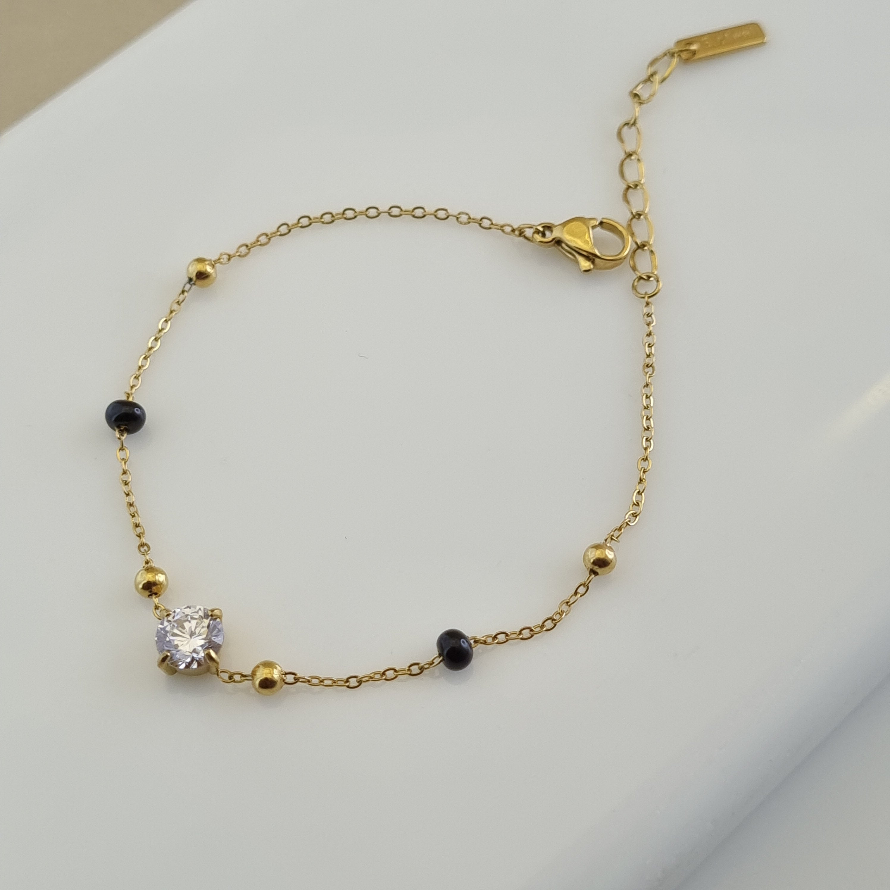Treshire 18K gold plated Nitya hand mangalsutra featuring black beads and a central solitaire crystal on a gold chain.