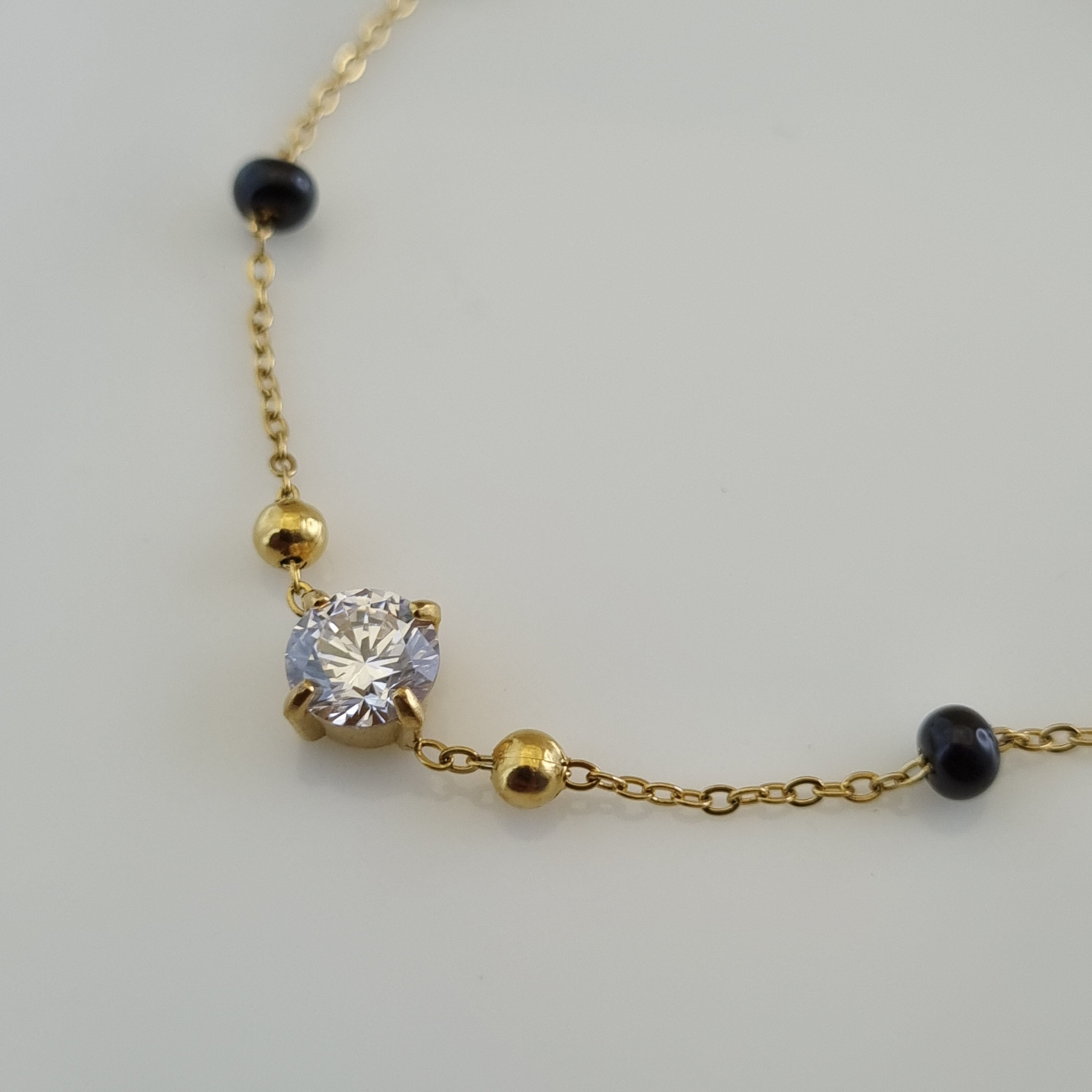 Treshire 18K gold plated Nitya hand mangalsutra featuring black beads and a central solitaire crystal on a gold chain.