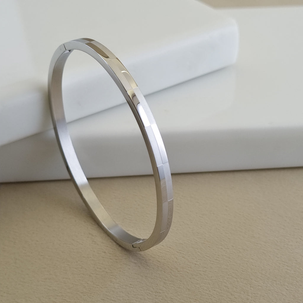 Treshire silver-tone Prism bangle with geometric faceted texture displayed on a white marble surface.