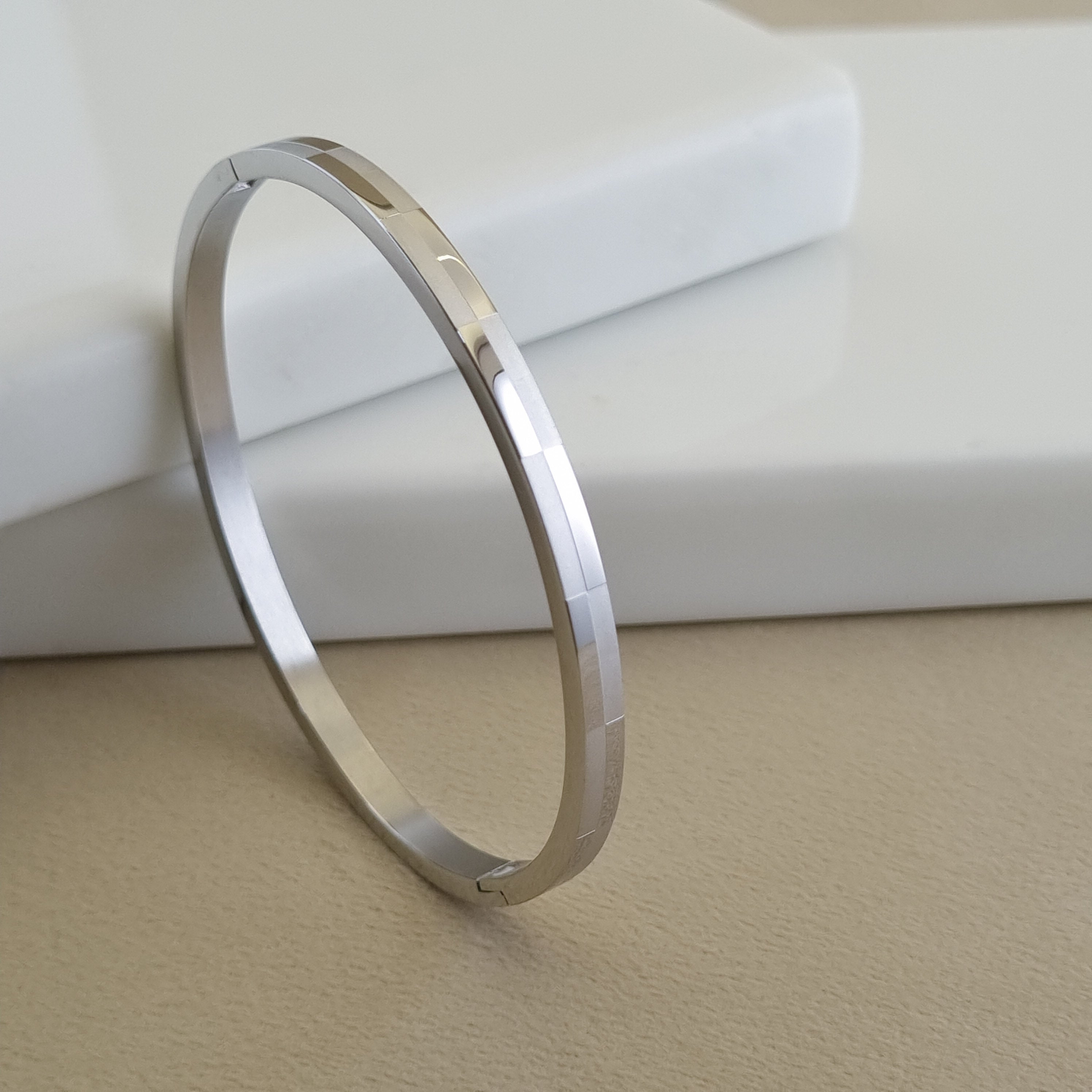 Treshire silver-tone Prism bangle with geometric faceted texture displayed on a white marble surface.