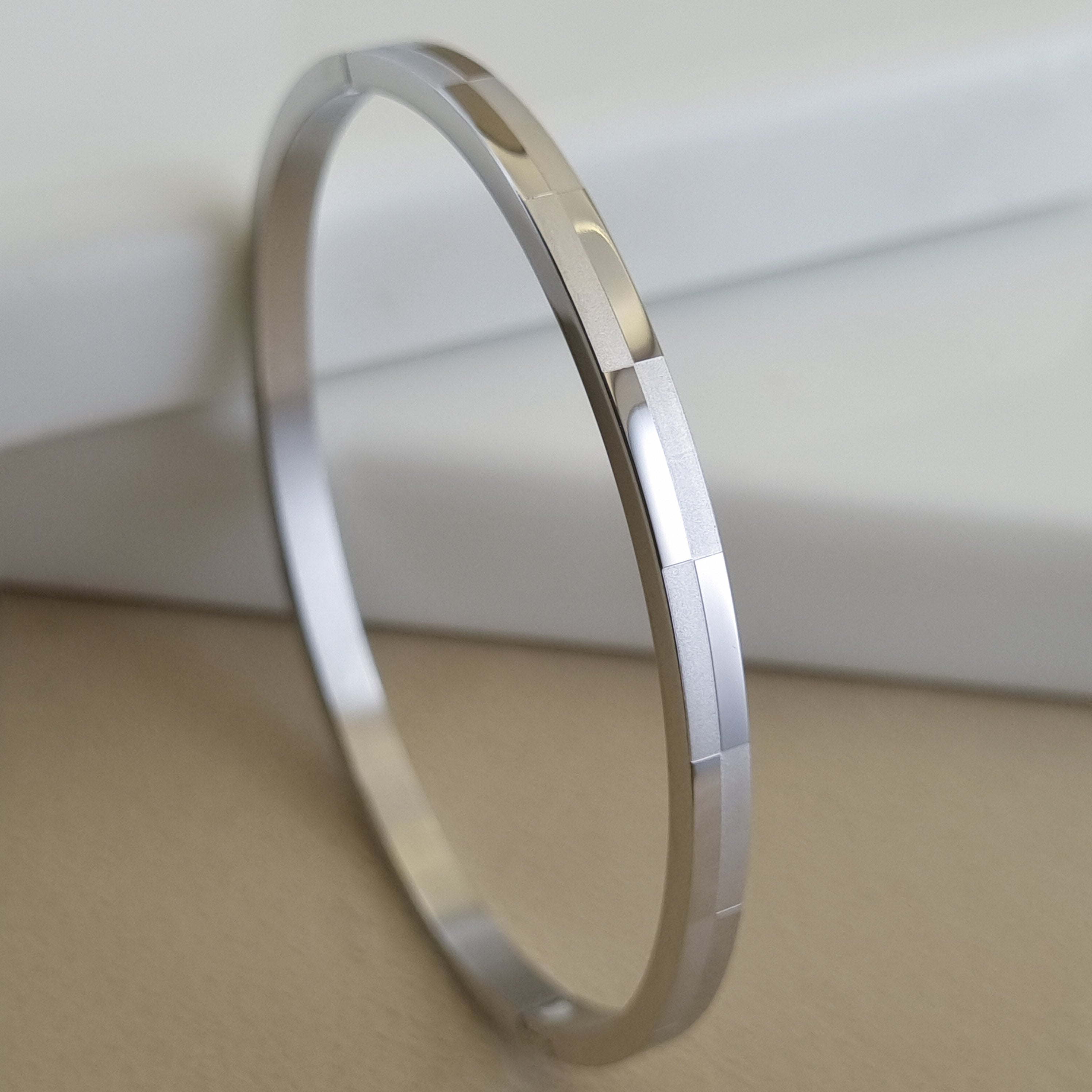 Treshire silver-tone Prism bangle with geometric faceted texture displayed on a white marble surface.