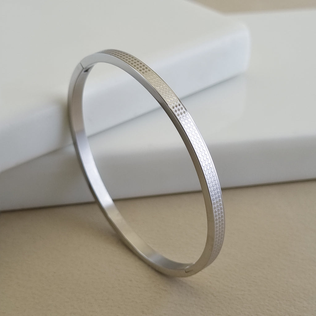 Treshire silver-tone Zenith bangle with a micro-diamond etched geometric pattern displayed on a white marble surface.