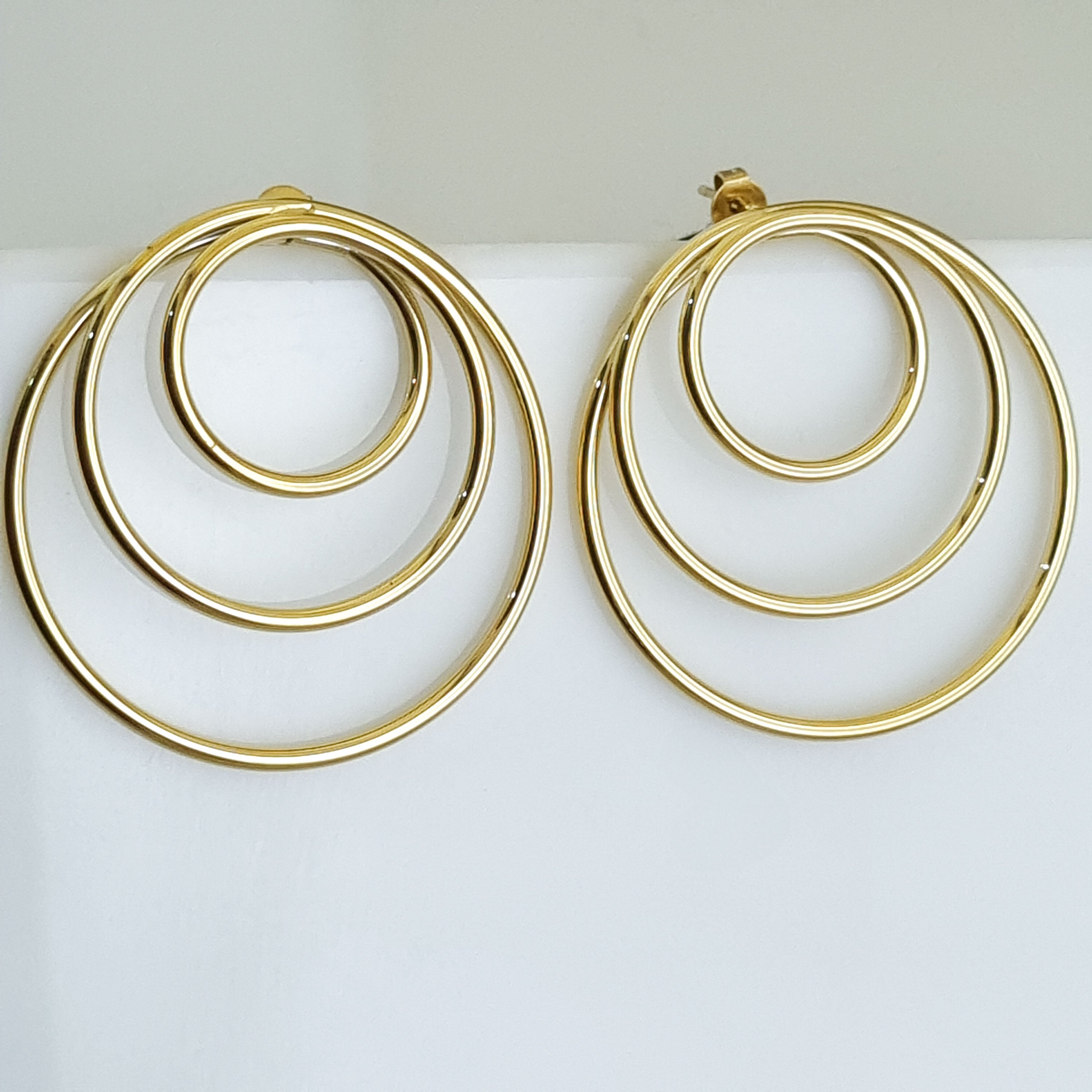Gold hoop earrings on a light gray background